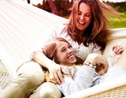 Foto di due donne sorridenti sdraiate su un’amaca.
