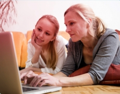 Foto di una madre e una figlia che usano assieme il computer. L’immagine illustra l’importanza della comunicazione e di aiutare tua figlia a trovare le informazioni giuste.