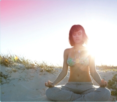 Foto di una donna seduta in meditazione sulla spiaggia. L’immagine illustra che è possibile rilassarsi e vivere normalmente anche durante il ciclo.